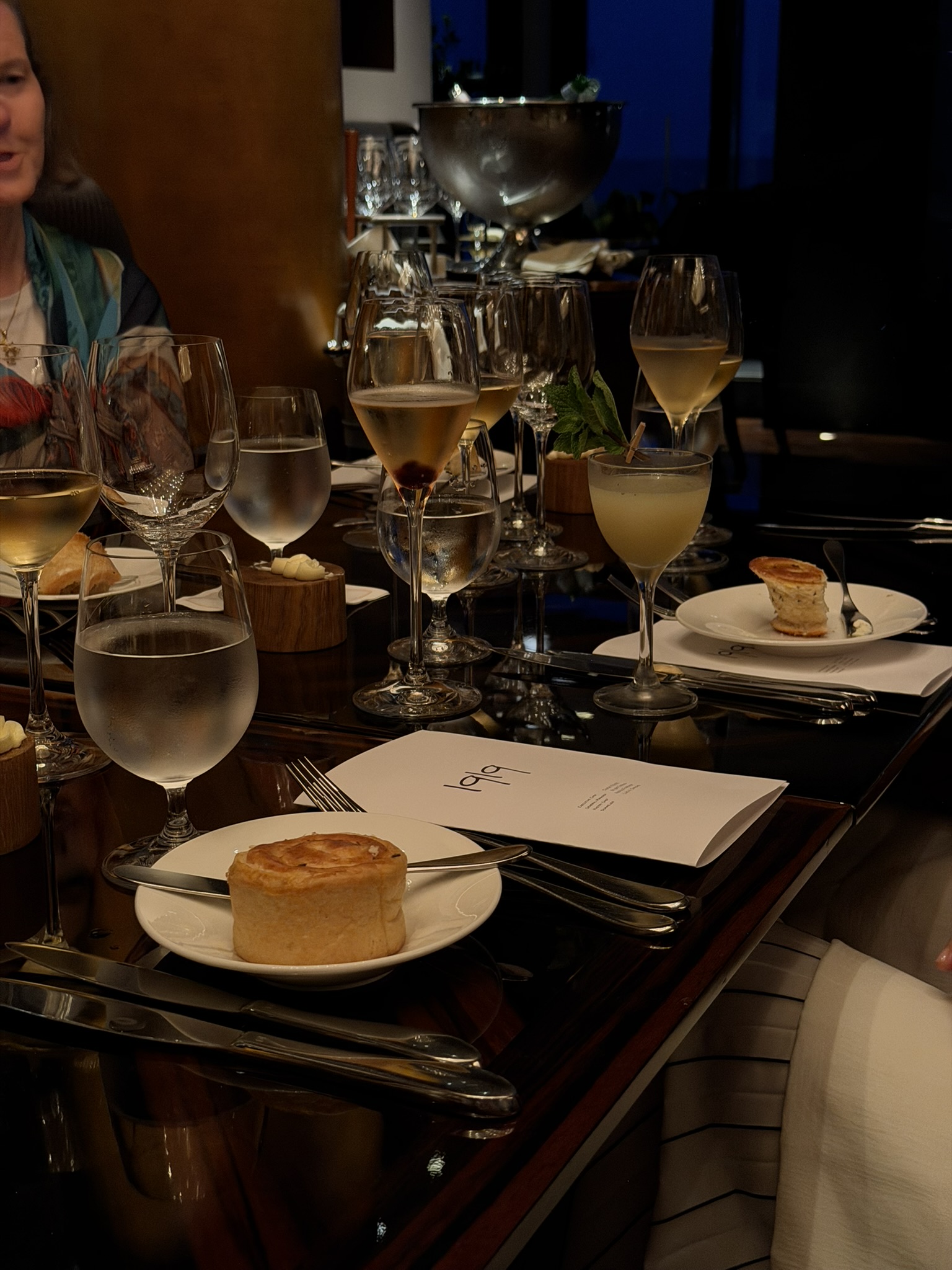 Formal dinner table with white wine, plated appetizers, and place settings in elegant venue