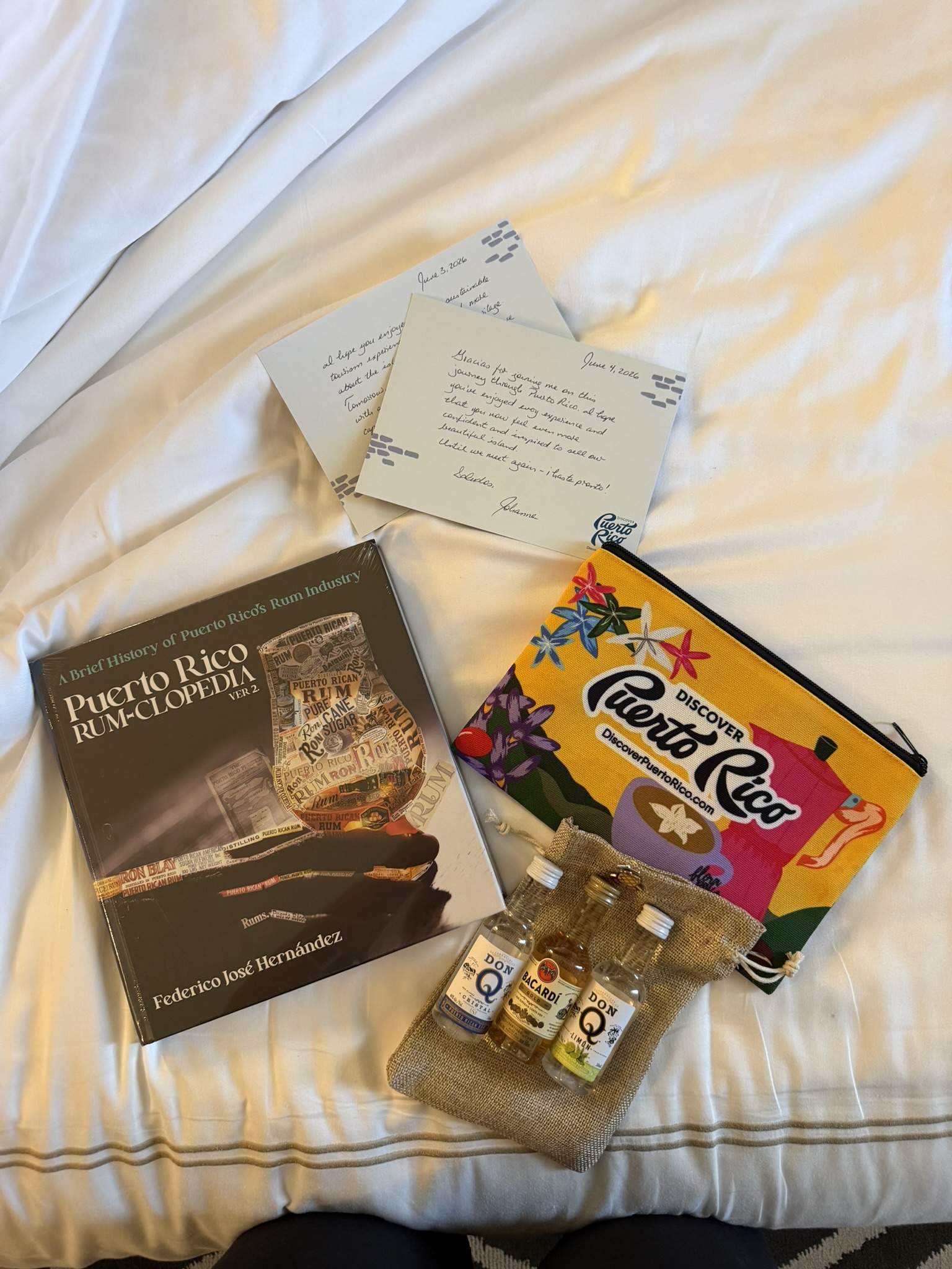 Handwritten letter and Puerto Rico rum encyclopedia with rum bottles on white bedding
