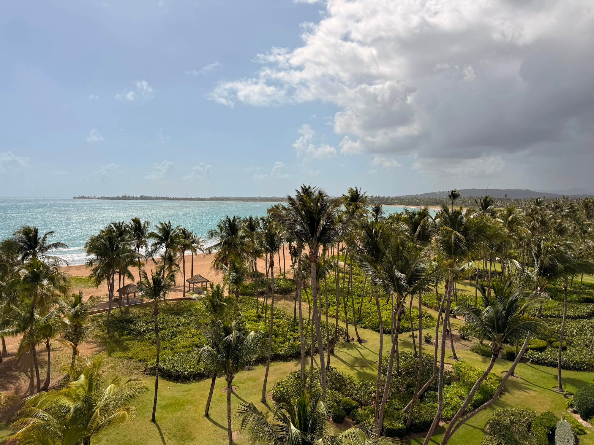 Aerial view of a beach resort with palm trees, sandy shore, and turquoise Caribbean waters