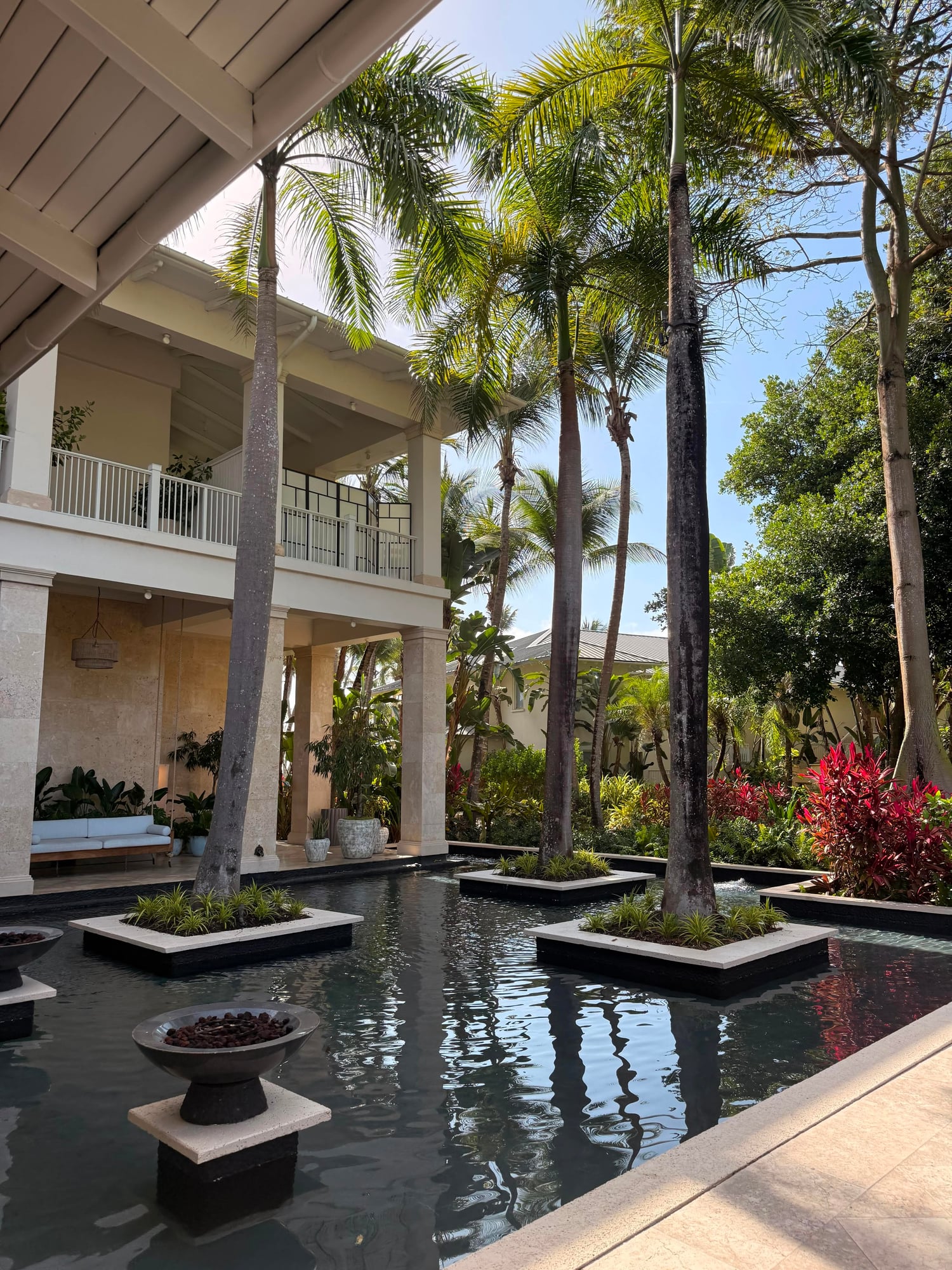 Modern white building with palm trees and reflecting pool in a tropical resort courtyard setting