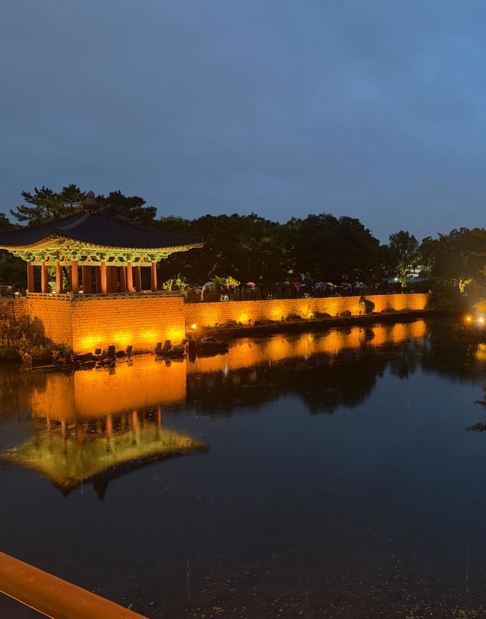 Illuminated traditional Korean pavilion reflected in still water at night