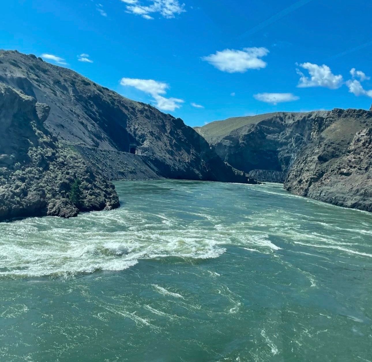 Turquoise glacial river flowing through a narrow canyon with steep rocky cliffs on both sides