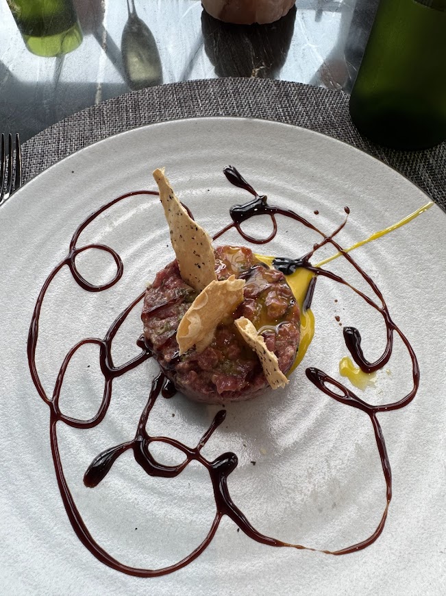 Artfully plated charcuterie and cured meat appetizer with decorative beet reduction on white plate