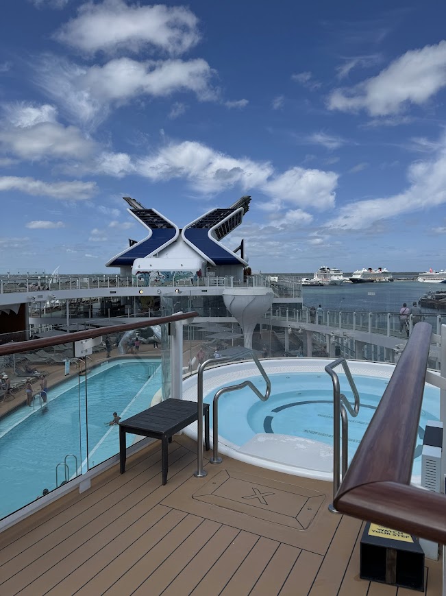 Ship's deck with white railings, pools, and distinctive blue and white sculptural funnel structure at sea