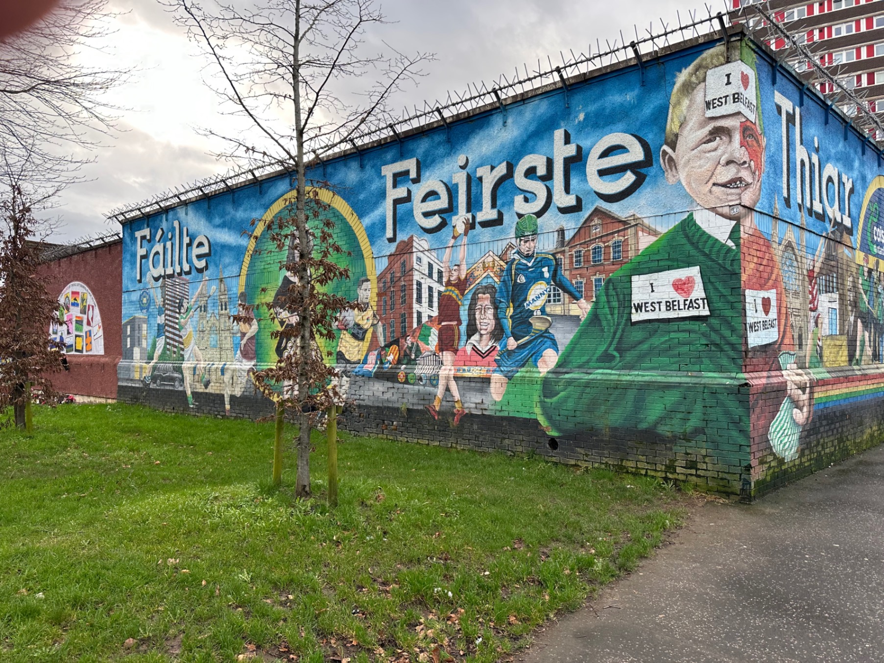 Street view in Belfast with murals on walls and mountains visible in the distance