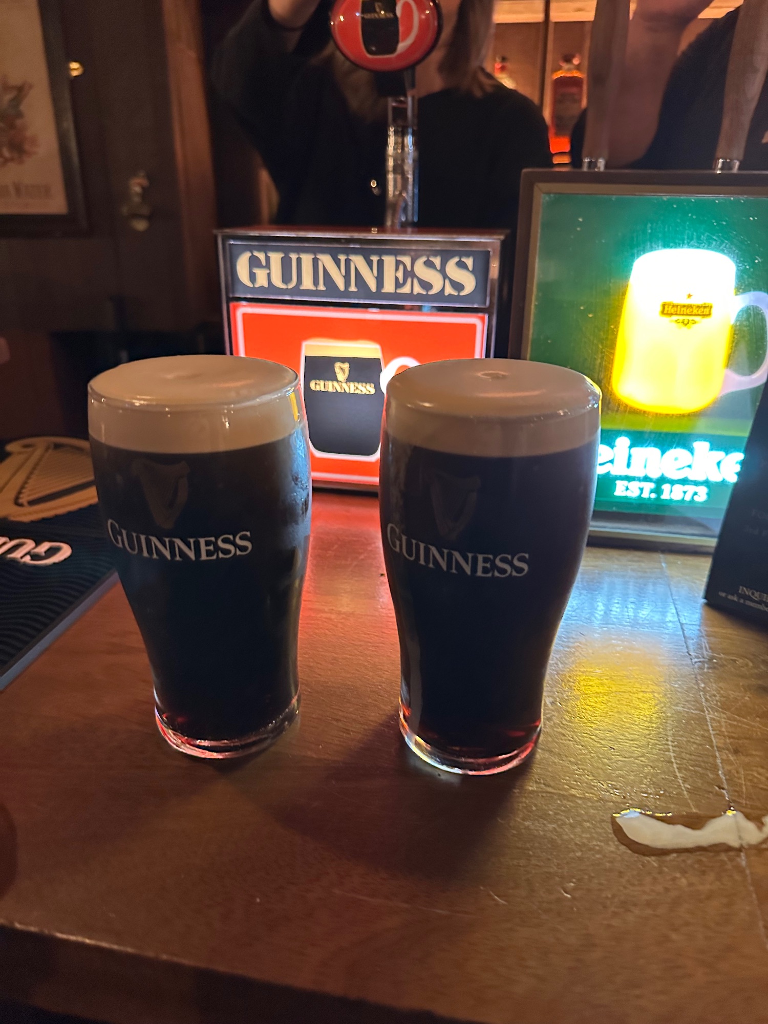 Man in blue jacket holding a glass of Irish coffee and a dark stone in a pub