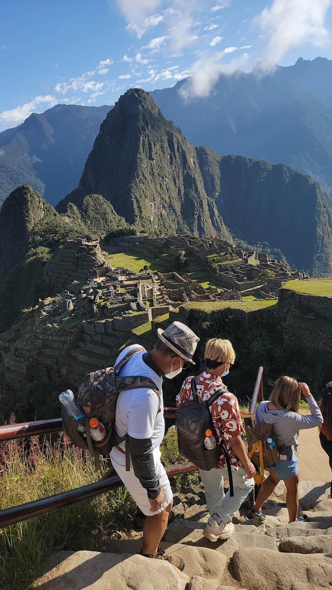 Hikers viewing Machu Picchu's terraced ruins and distinctive peak from an elevated viewpoint on the trail