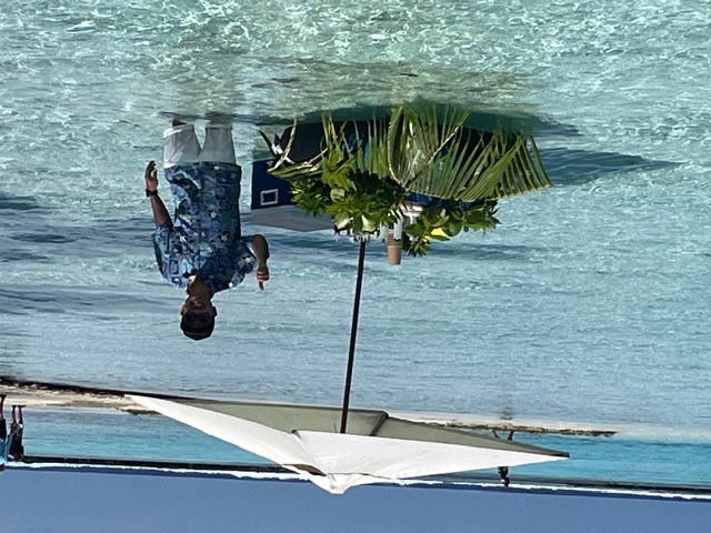 Distant view of palm-covered island across turquoise water under blue sky