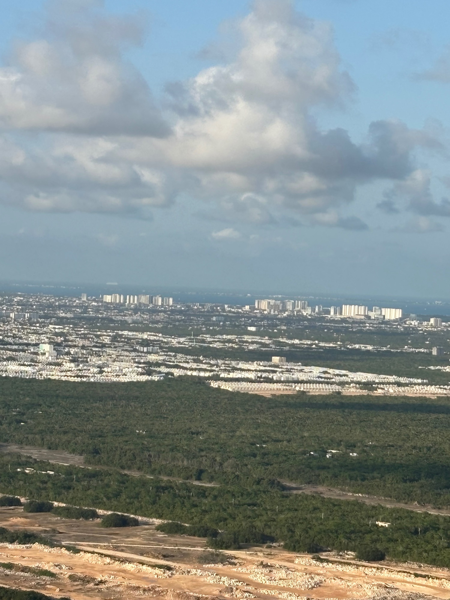 Aerial view of Cancun's sprawling coastal development with white buildings, green forest, and waterways