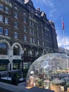Historic stone building with arched windows and a large geodesic dome structure on the street in front