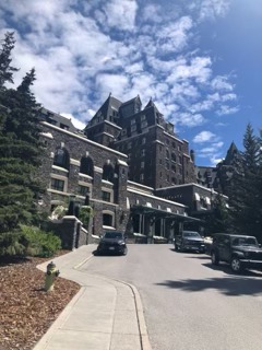 Stone castle-style hotel building with turrets set against a mountain backdrop on a sunny day