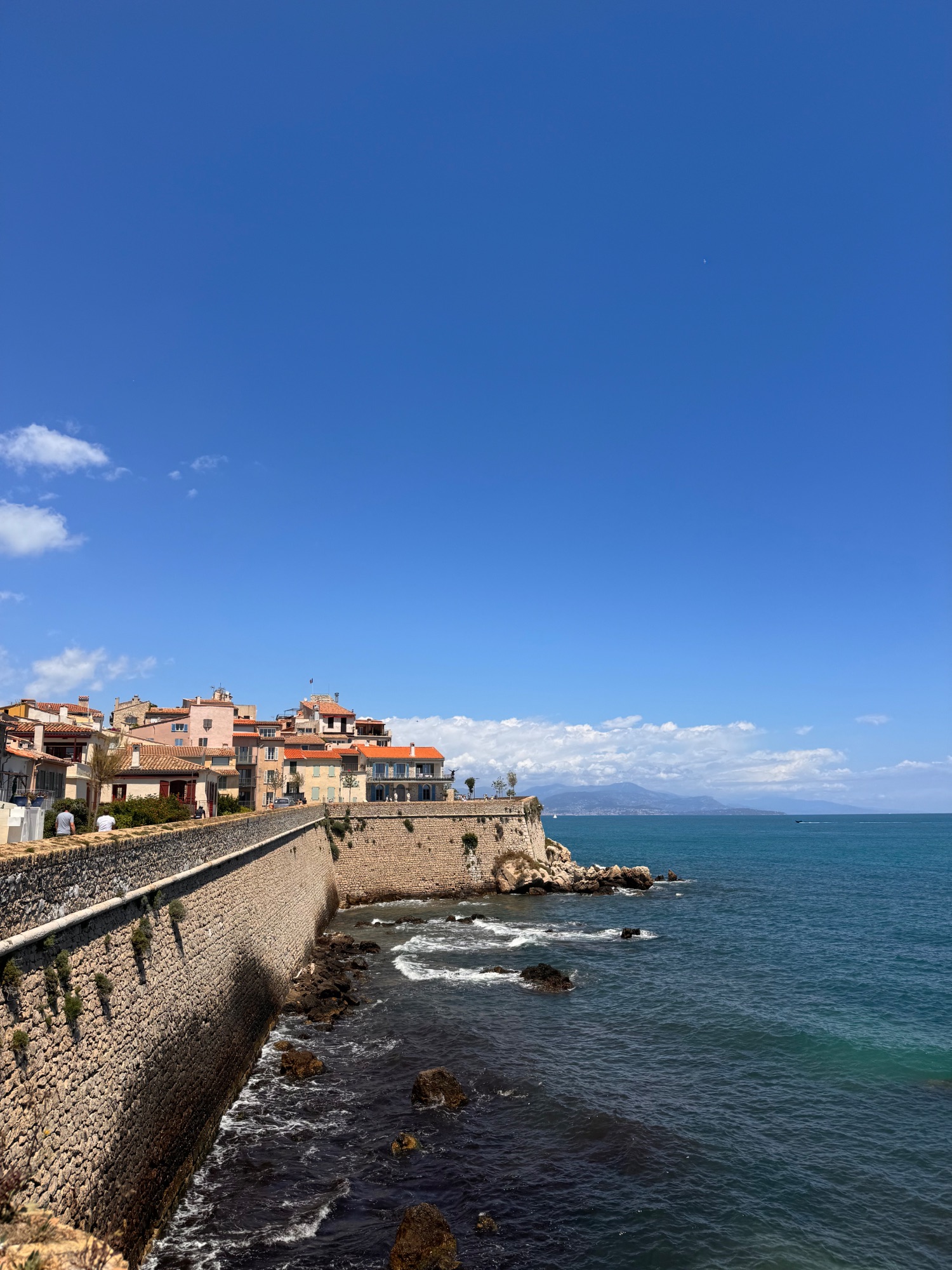 Coastal village with terracotta-roofed buildings perched on rocky cliffs overlooking turquoise Mediterranean Sea