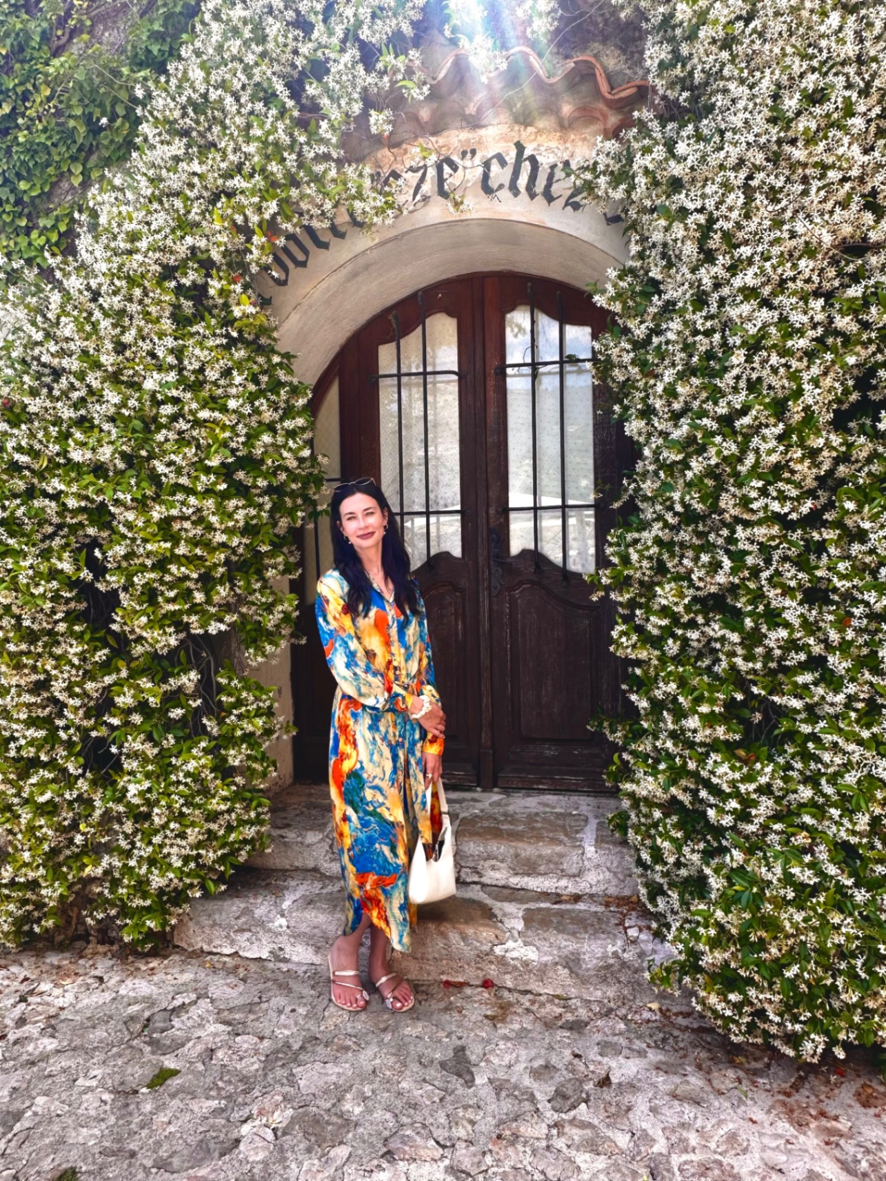 Ivy-covered stone archway entrance to restaurant with woman in colorful patterned dress posing in doorway