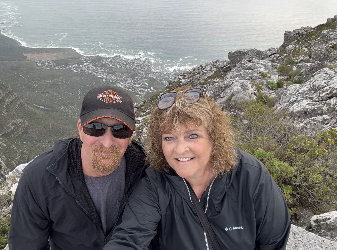 Couple at clifftop viewpoint overlooking misty forested valley with dramatic rocky outcrops in South Africa