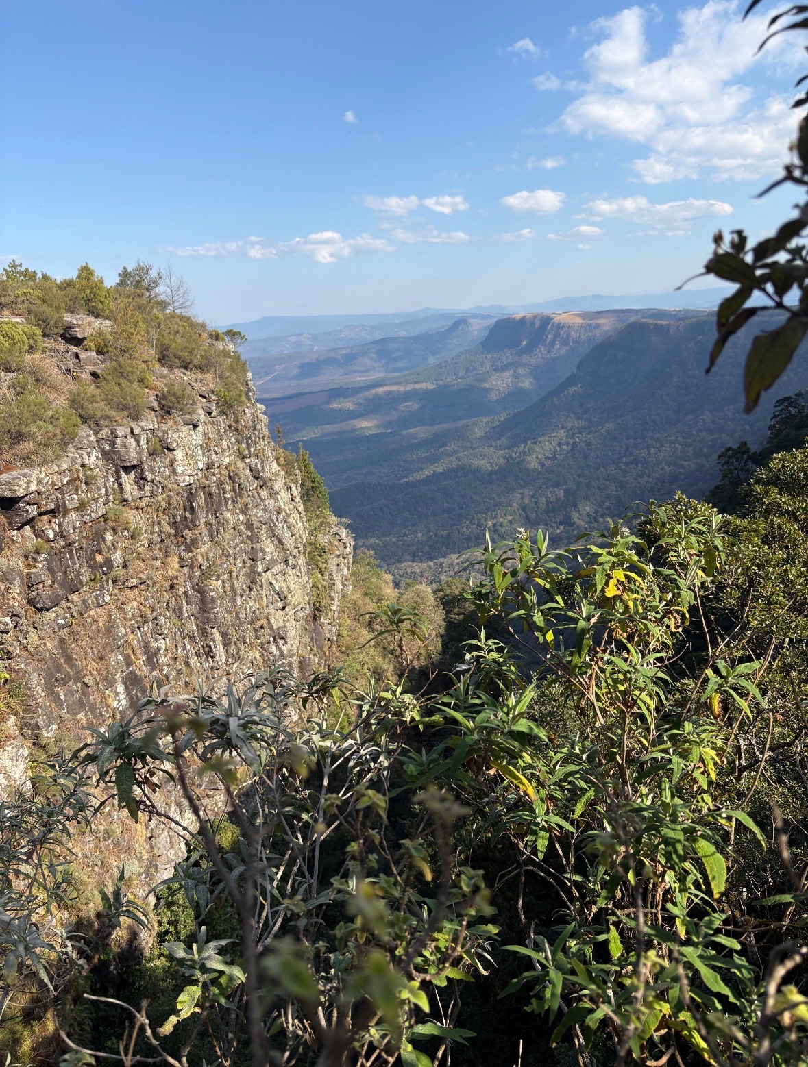 Deep rocky canyon with waterfall and blue rope visible, showing geological formations in natural landscape