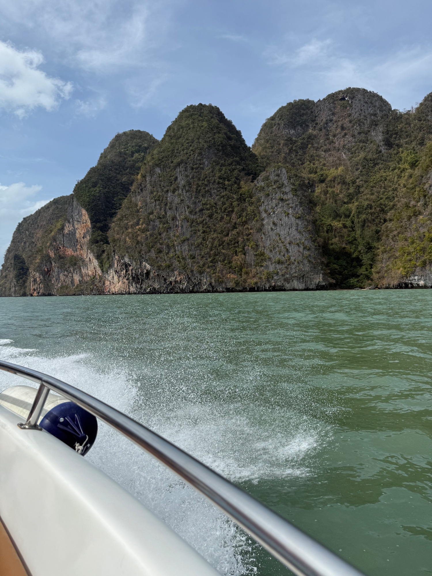 Limestone cliffs and forested islands viewed from a boat on turquoise Phang Nga Bay waters
