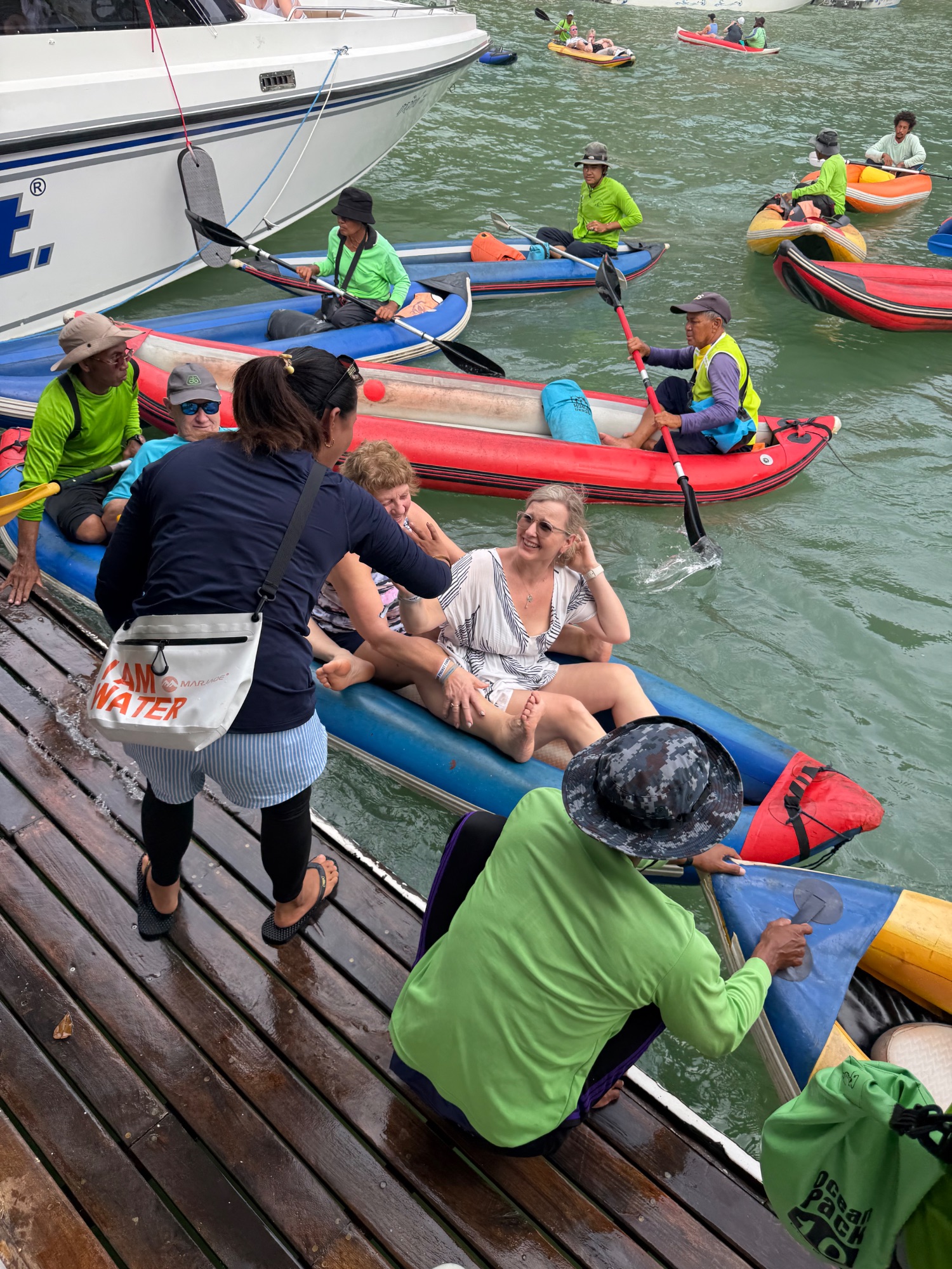 Multiple colorful kayaks and boats lined up at a dock with tourists preparing for water activities