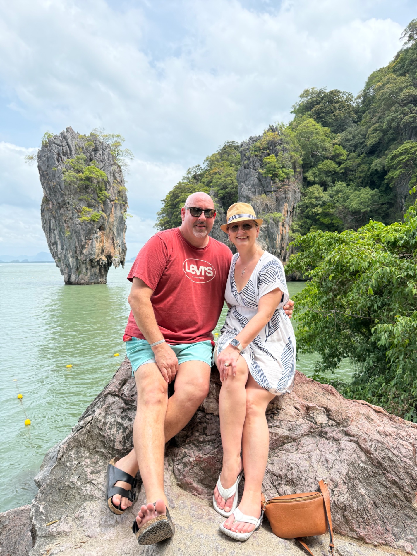 Couple posing on a rock formation with dramatic limestone cliffs and turquoise water behind them
