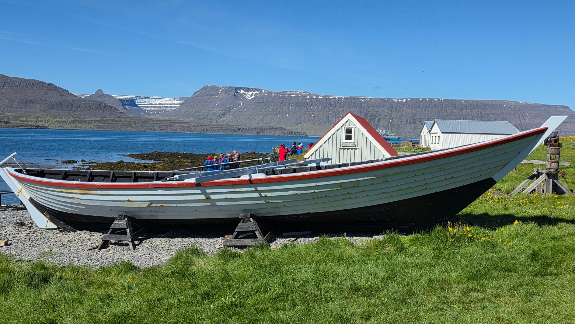Traditional Icelandic fishing boat with red and white trim beached on gravel shore