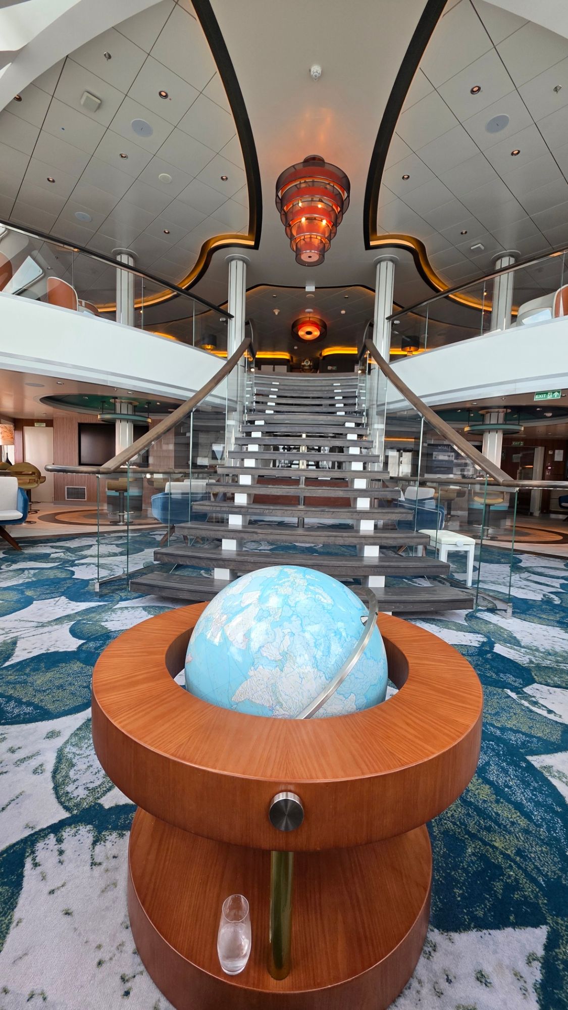 Modern cruise ship interior atrium with globe sculpture and geometric ceiling design