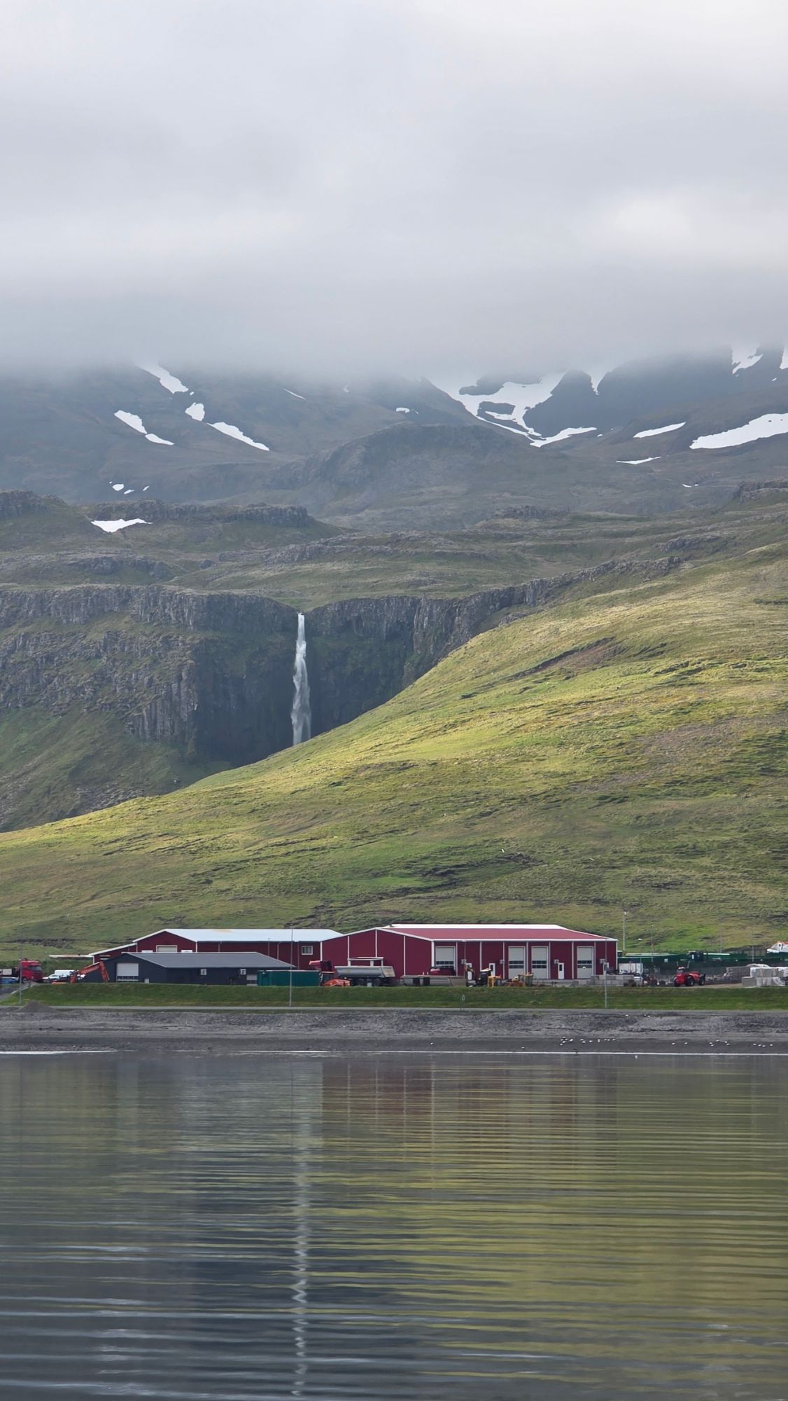 Colorful houses reflected in still water along Icelandic fjord settlement