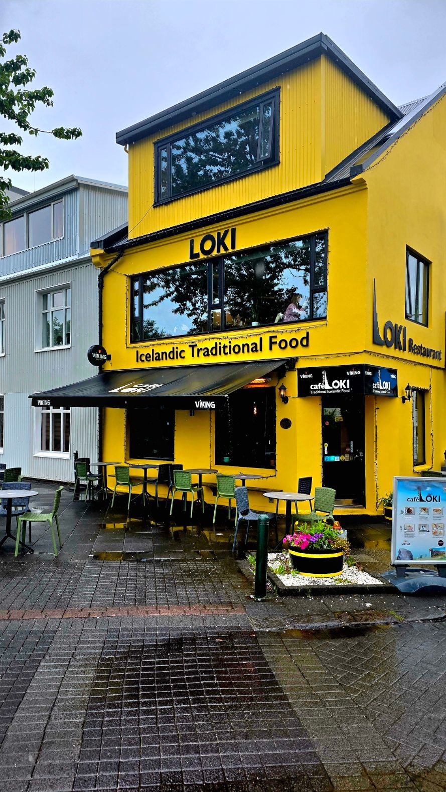 Bright yellow restaurant building with black trim in Icelandic town setting