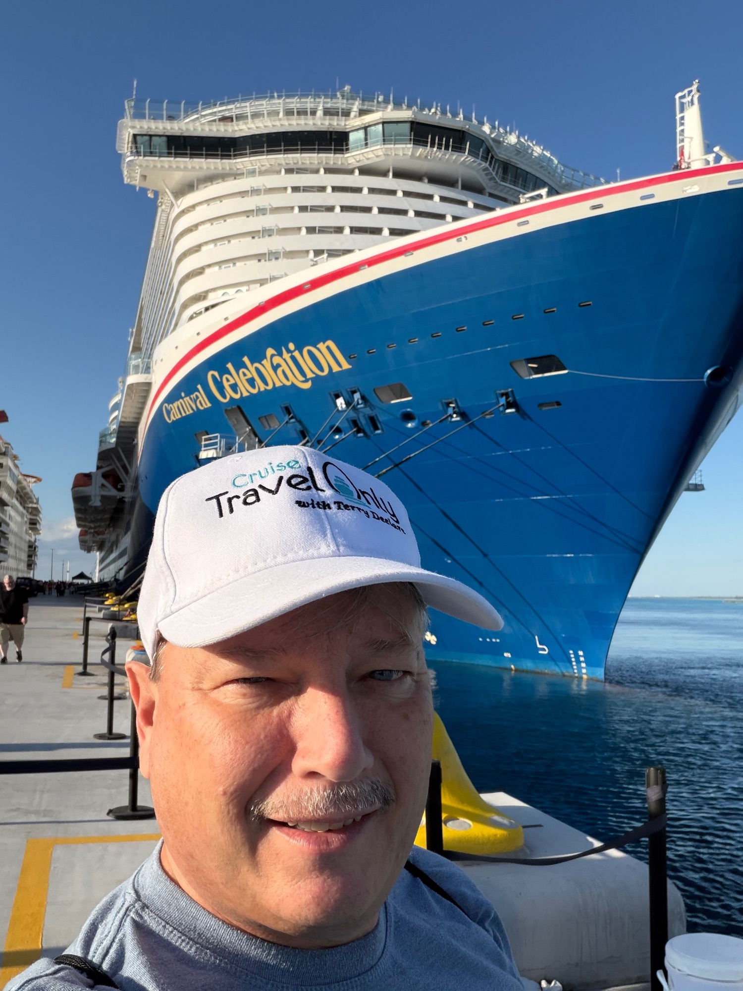 Terry Declare in Travel Only cap standing in front of Carnival Celebration ship at dock