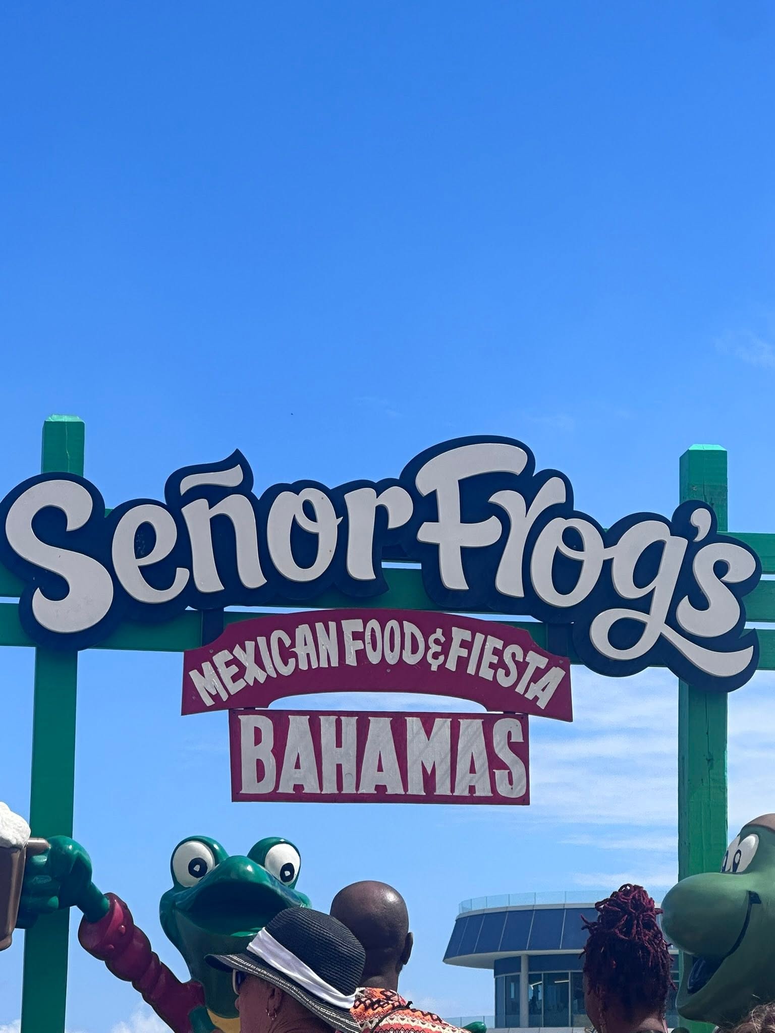 Señor Frog's Mexican Food & Fiesta sign with green frog mascot statues under clear blue sky in the Bahamas
