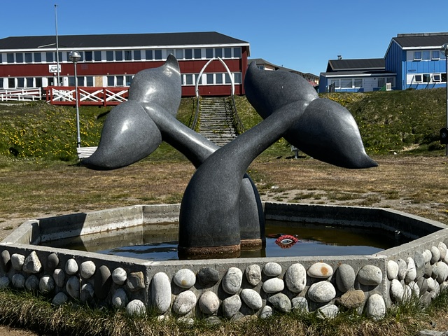 Man paddles a traditional Greenlandic kayak on calm blue water