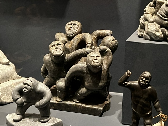 Five traditional Greenlandic tupilak dolls with beaded clothing displayed in a museum case
