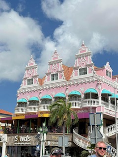 Colorful pink and turquoise colonial-style building with ornate architecture and palm trees in Aruba