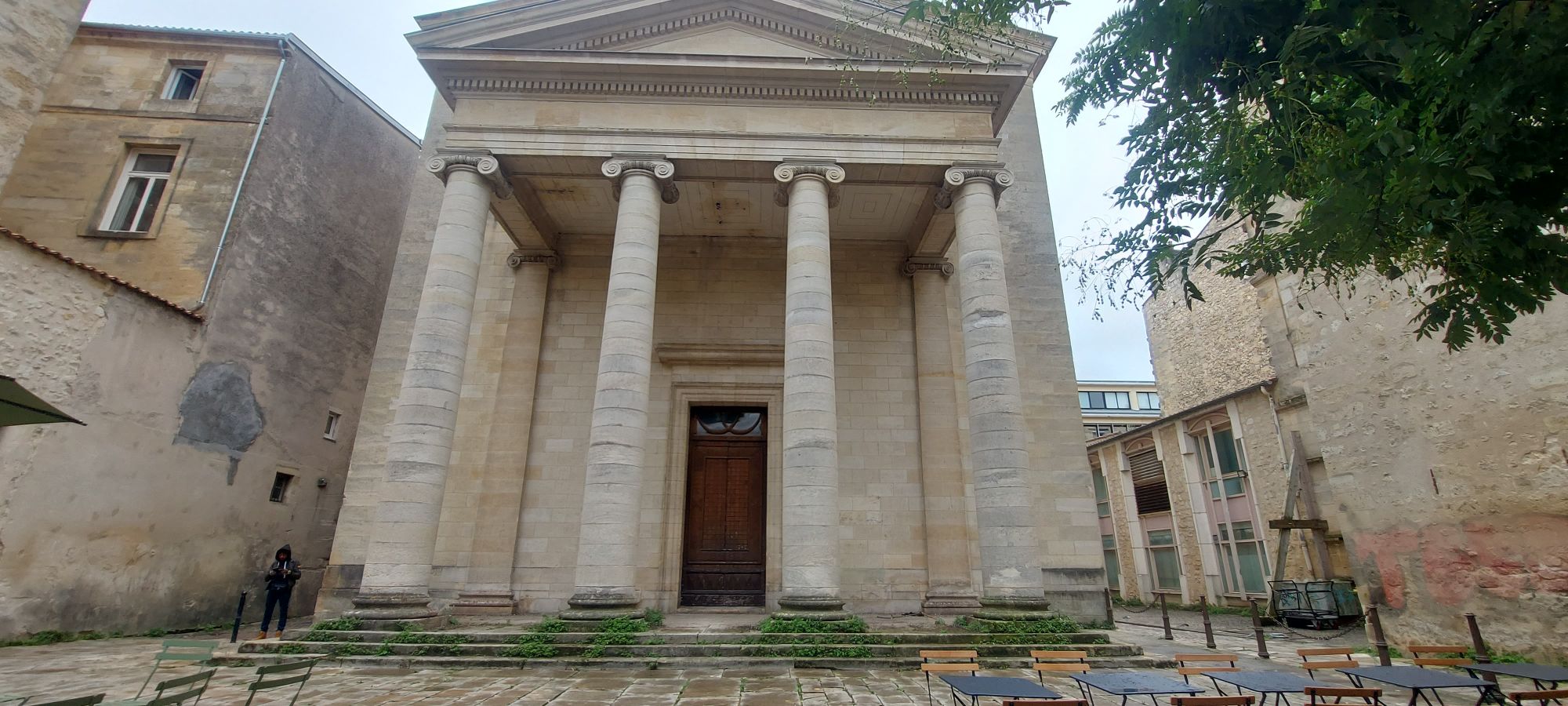 Neoclassical chapel with four tall columns and a triangular pediment in a French town square