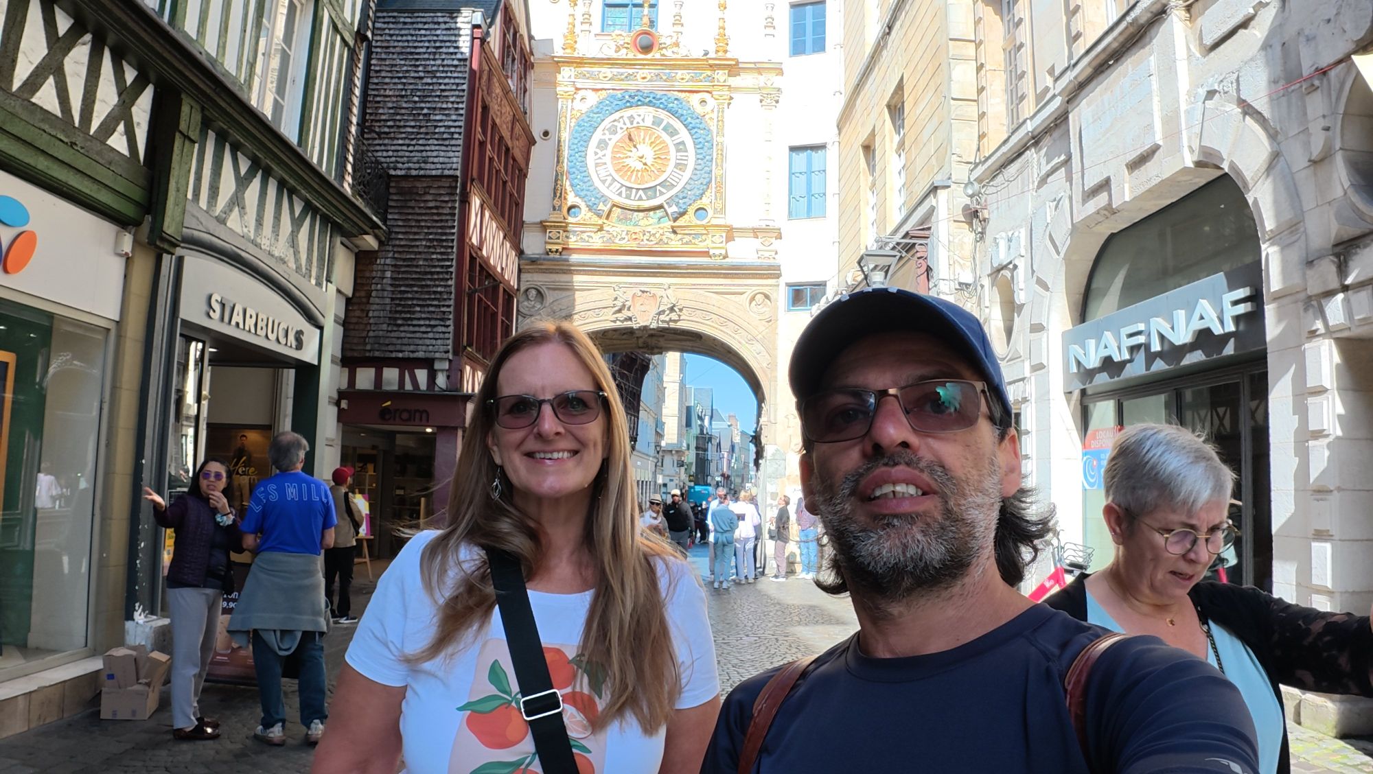 Victoria and companion in a town square framed by half-timbered buildings and storefronts