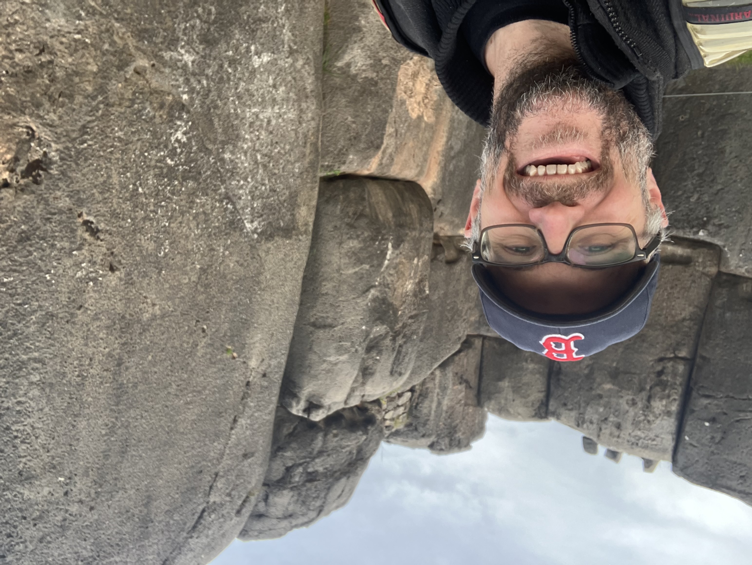 Brian wearing a Red Sox cap smiling at ancient Incan stone walls with precisely fitted large granite blocks