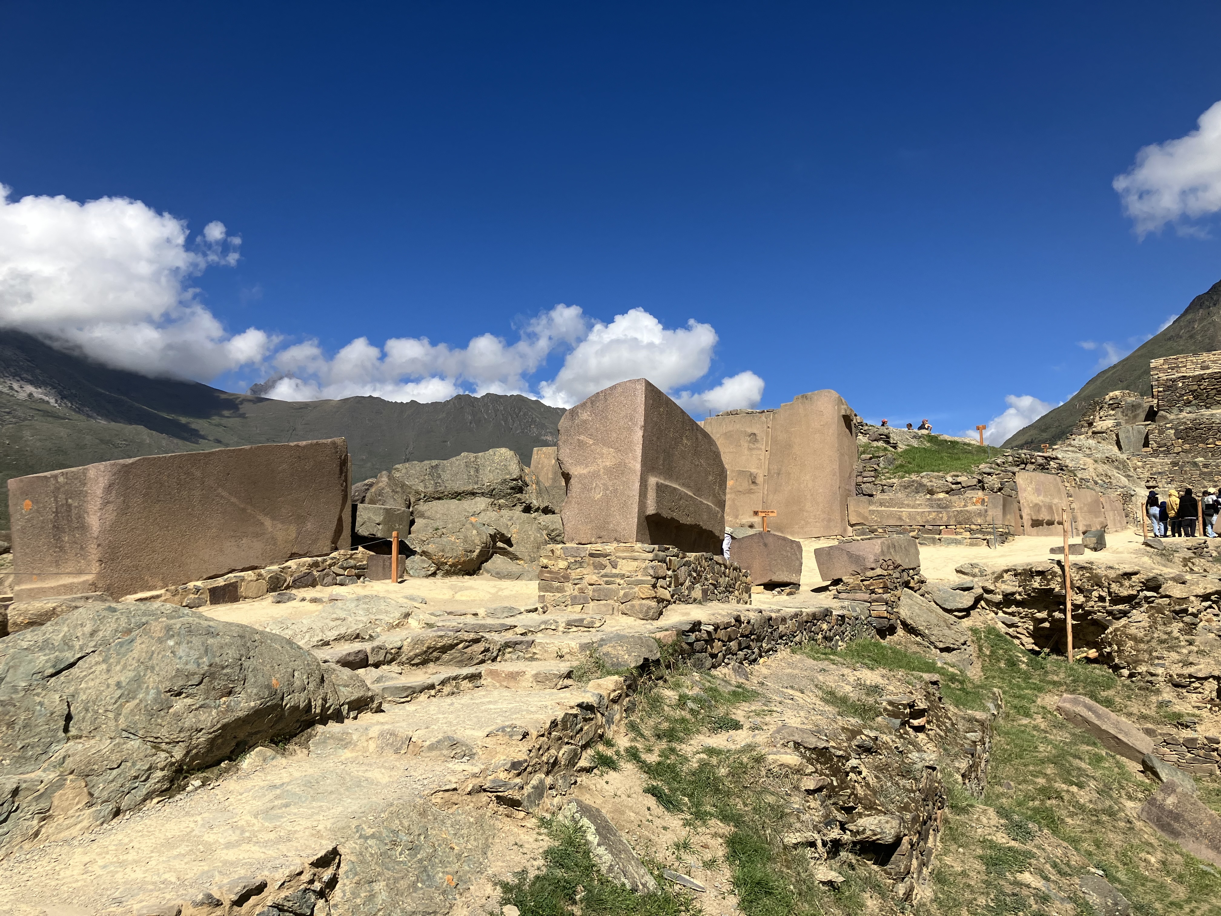 Incan temple structure with massive stone walls and doorways set against a dramatic mountain backdrop and valley below