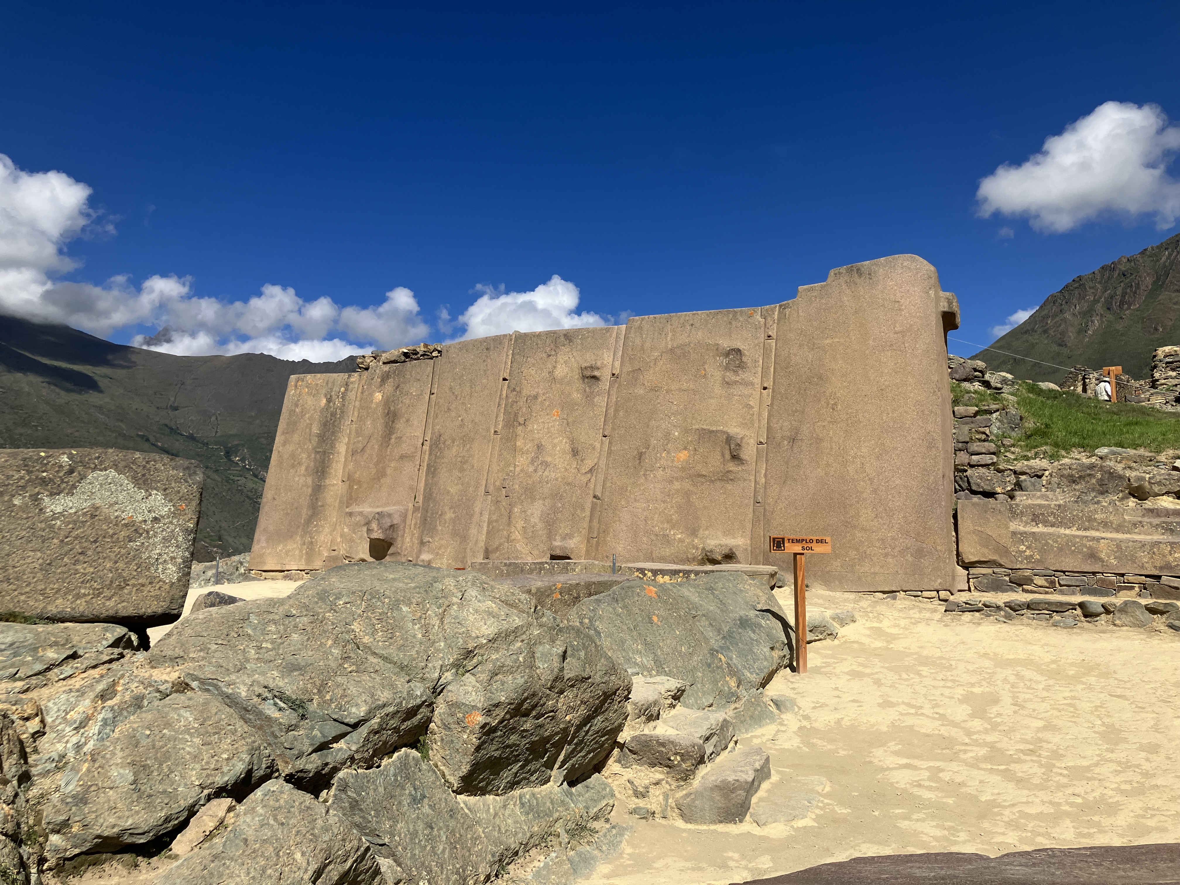 Close-up of Incan stonework showing large fitted granite blocks with orange lichen and a narrow stone stairway
