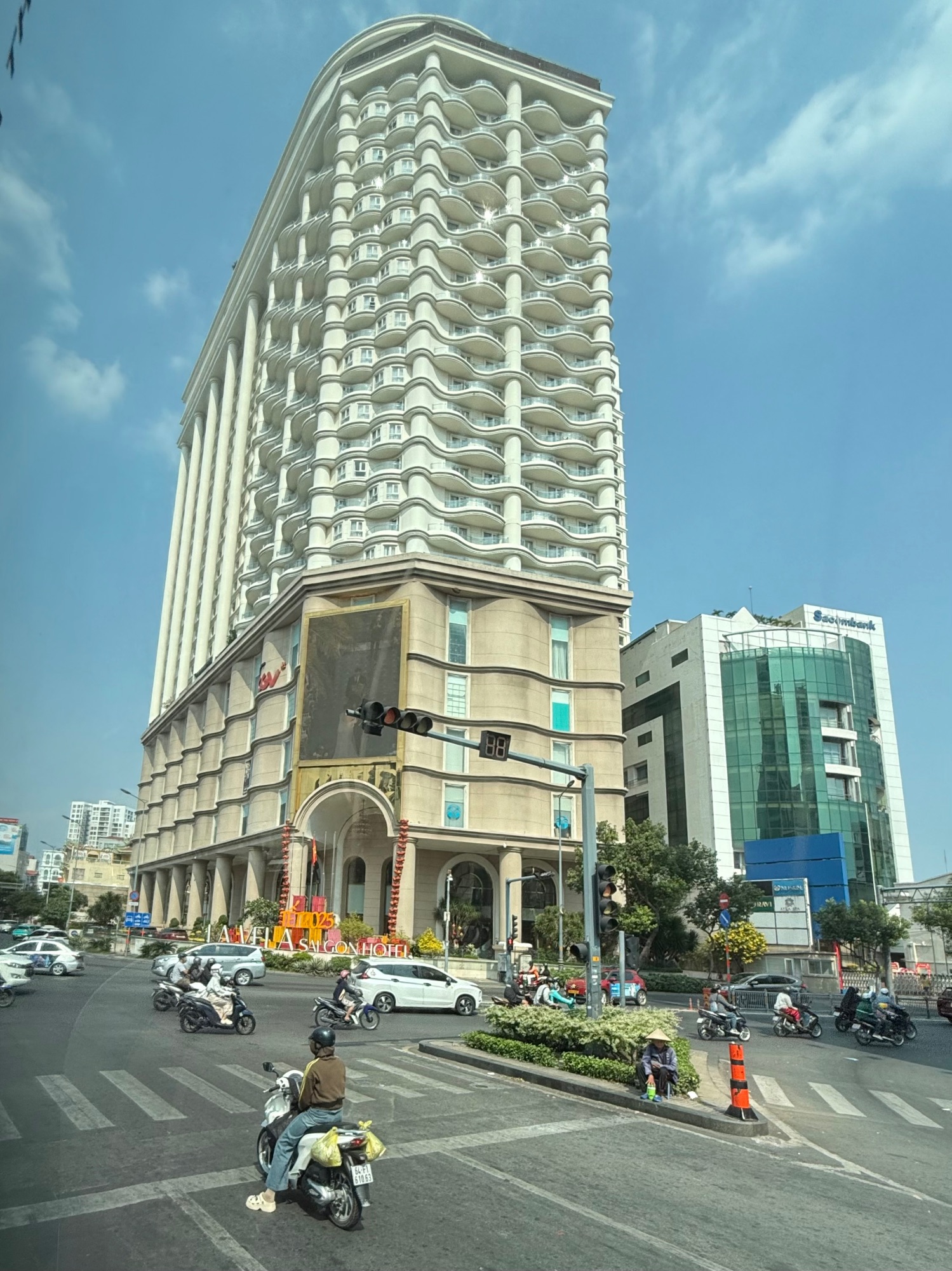 Ornate white and cream high-rise hotel building with distinctive wavy balconies on a Saigon street corner