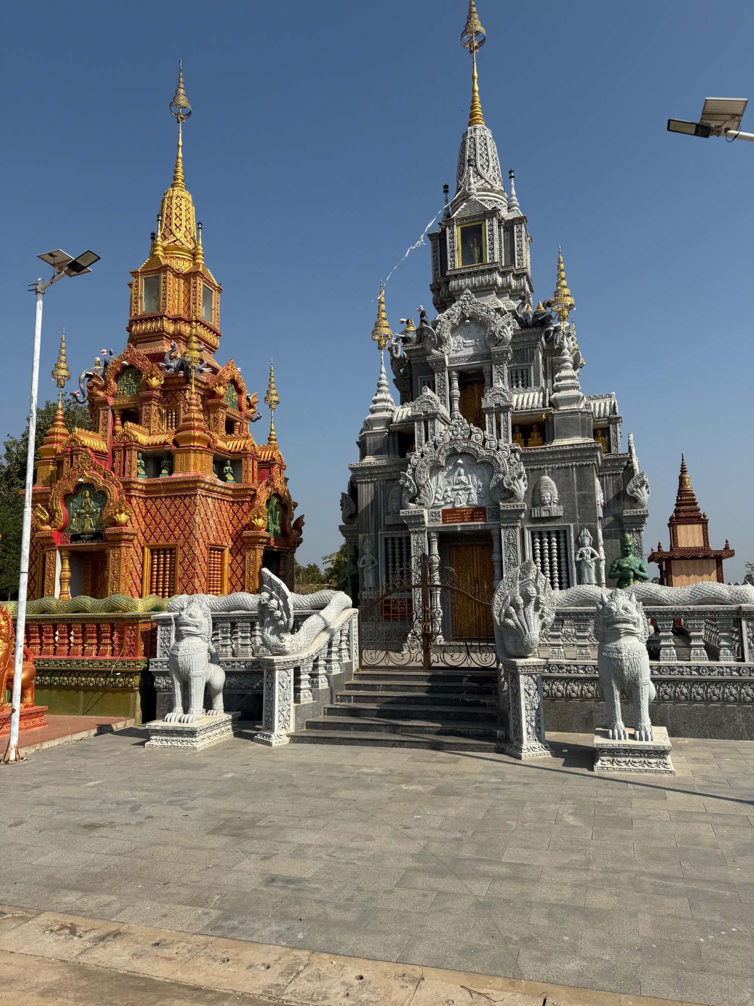 Ornate red and white Cambodian temple structures with intricate carvings and guardian lion statues