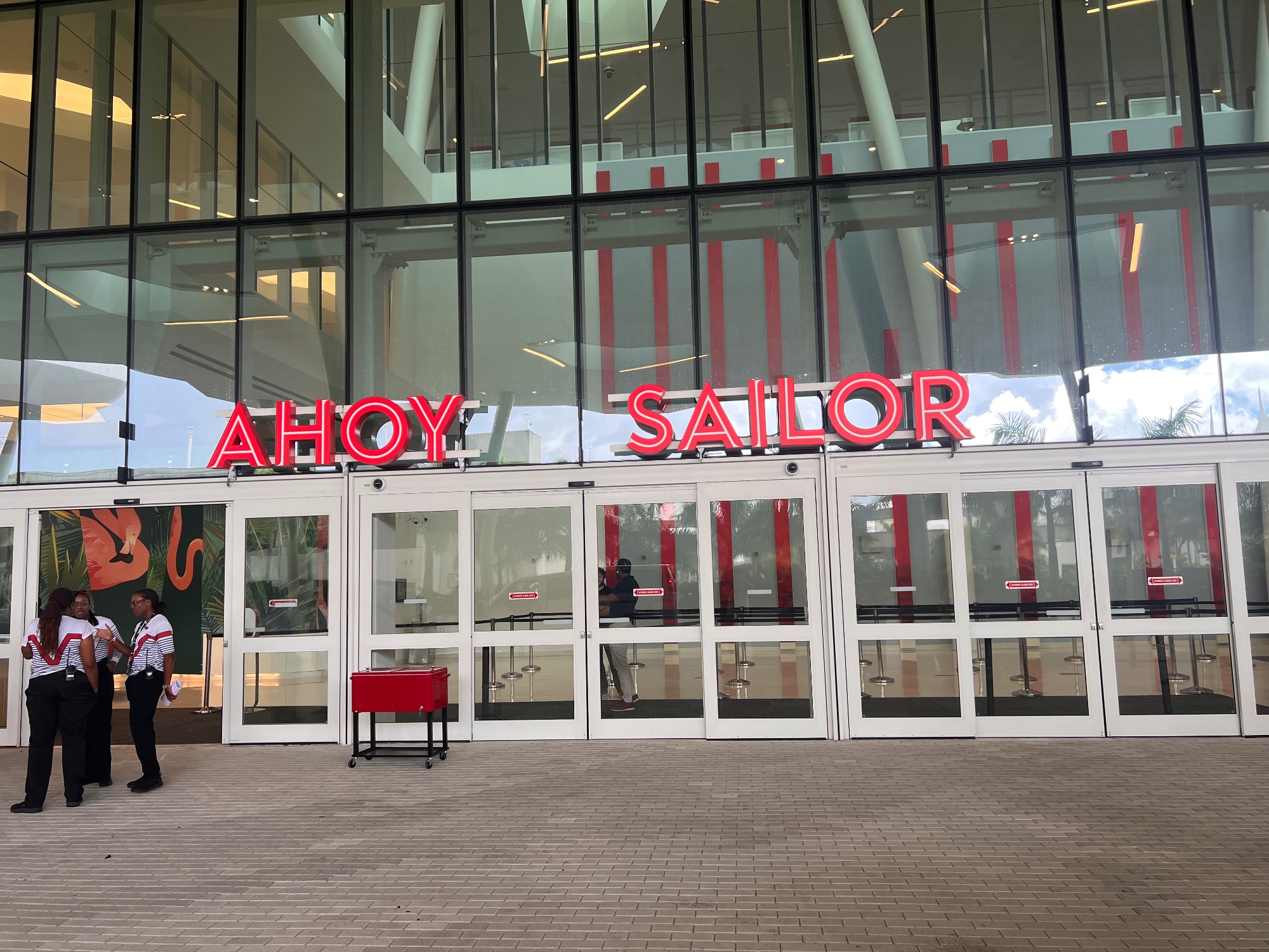 Red neon AHOY SAILOR signs above glass entrance doors to a cruise ship terminal