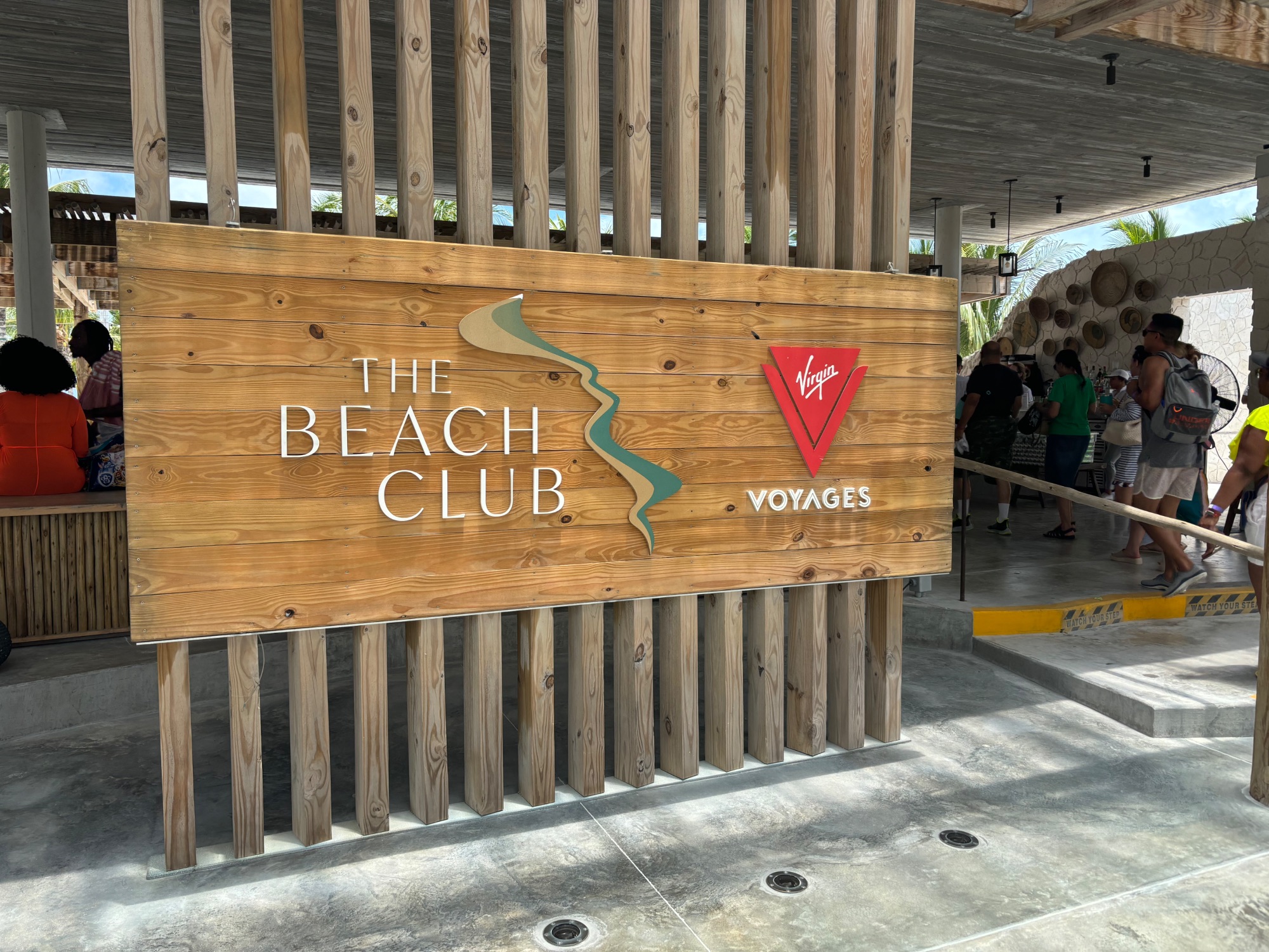Wooden sign reading THE BEACH CLUB with Virgin Voyages logo at a cruise terminal entrance