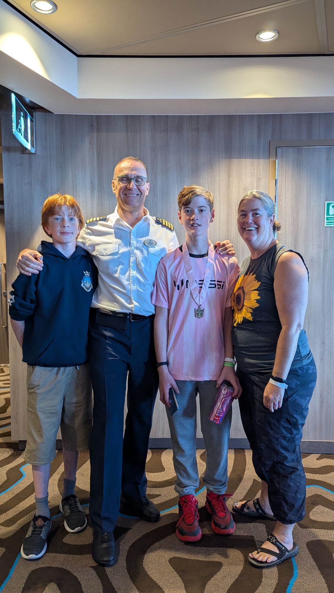 Marcy Bond with family members and ship officer in corridor aboard Anthem of the Seas
