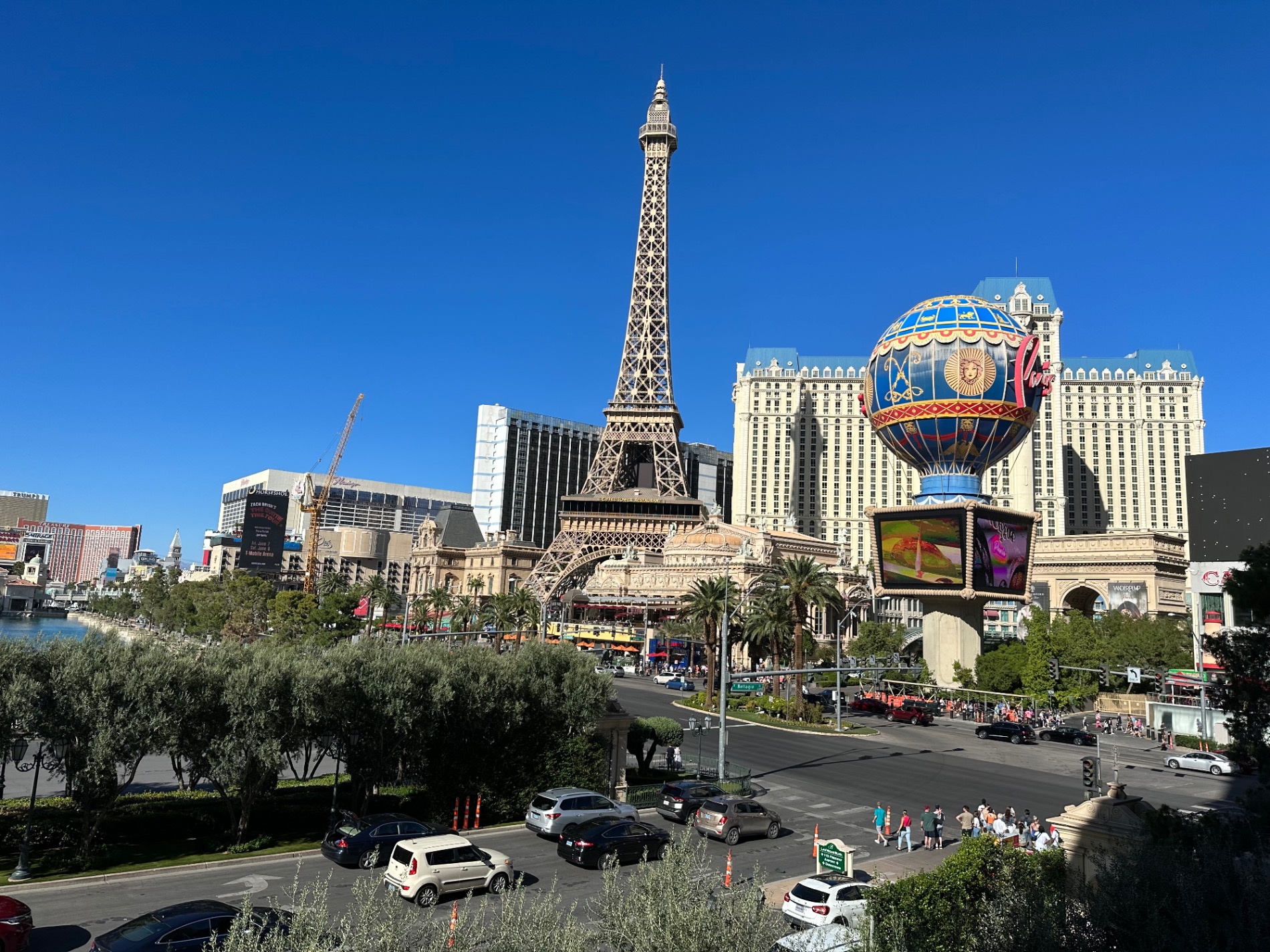 Las Vegas Strip daytime view with Eiffel Tower replica, Paris Las Vegas hotel, and hot air balloon sign against clear blue sky