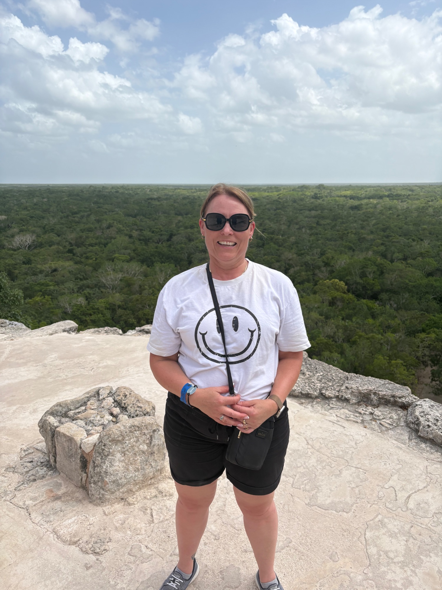 Ancient Mayan stone ruins with a pyramid structure visible among jungle vegetation