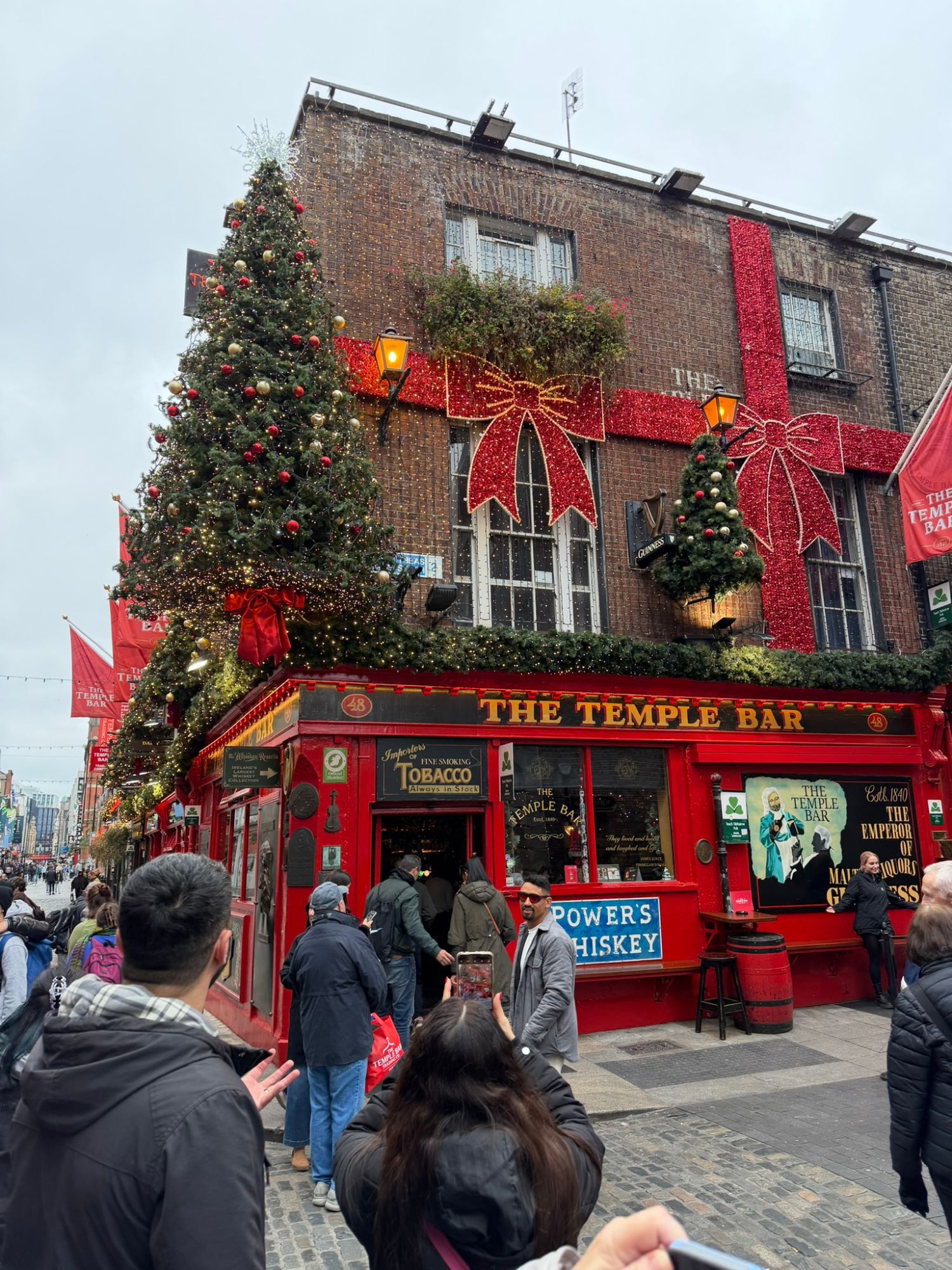 The Temple Bar pub decorated with Christmas garland, red bows, and festive lights on Dublin street