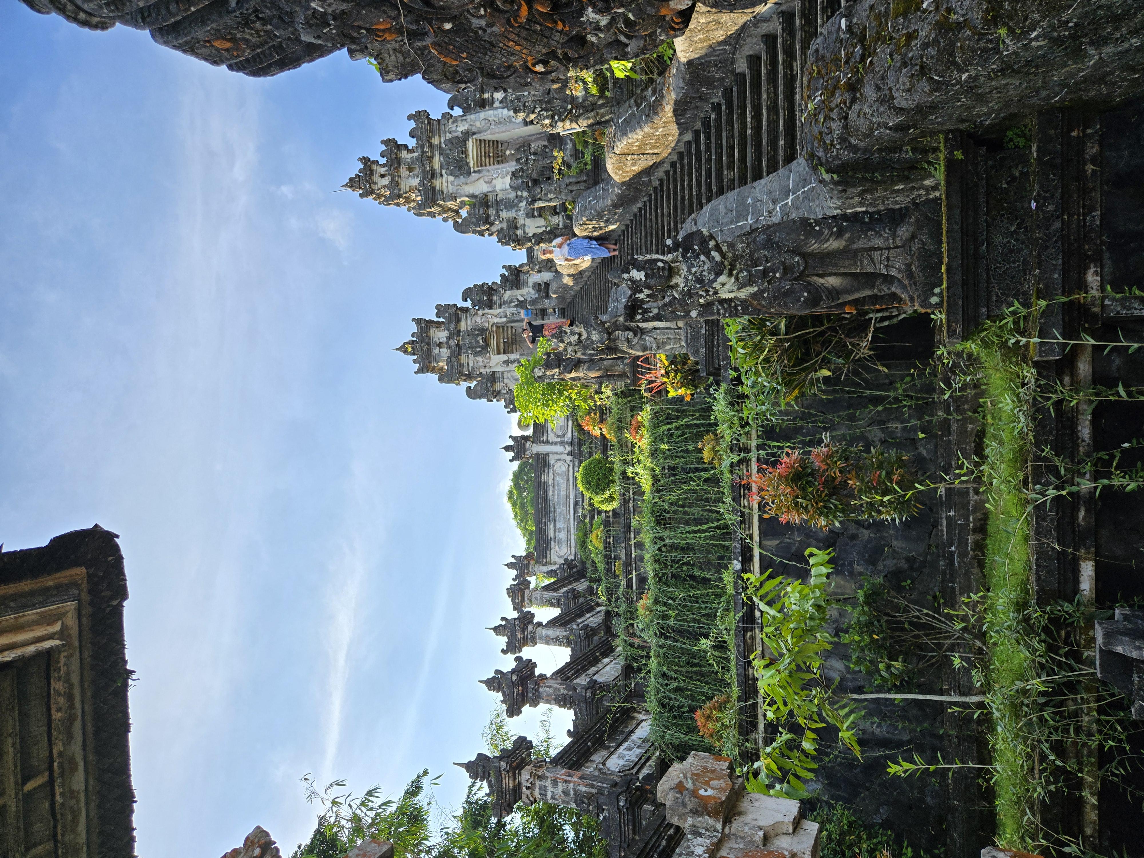 Stone temple steps leading upward with carved guardian statues on either side, surrounded by vegetation and tourists