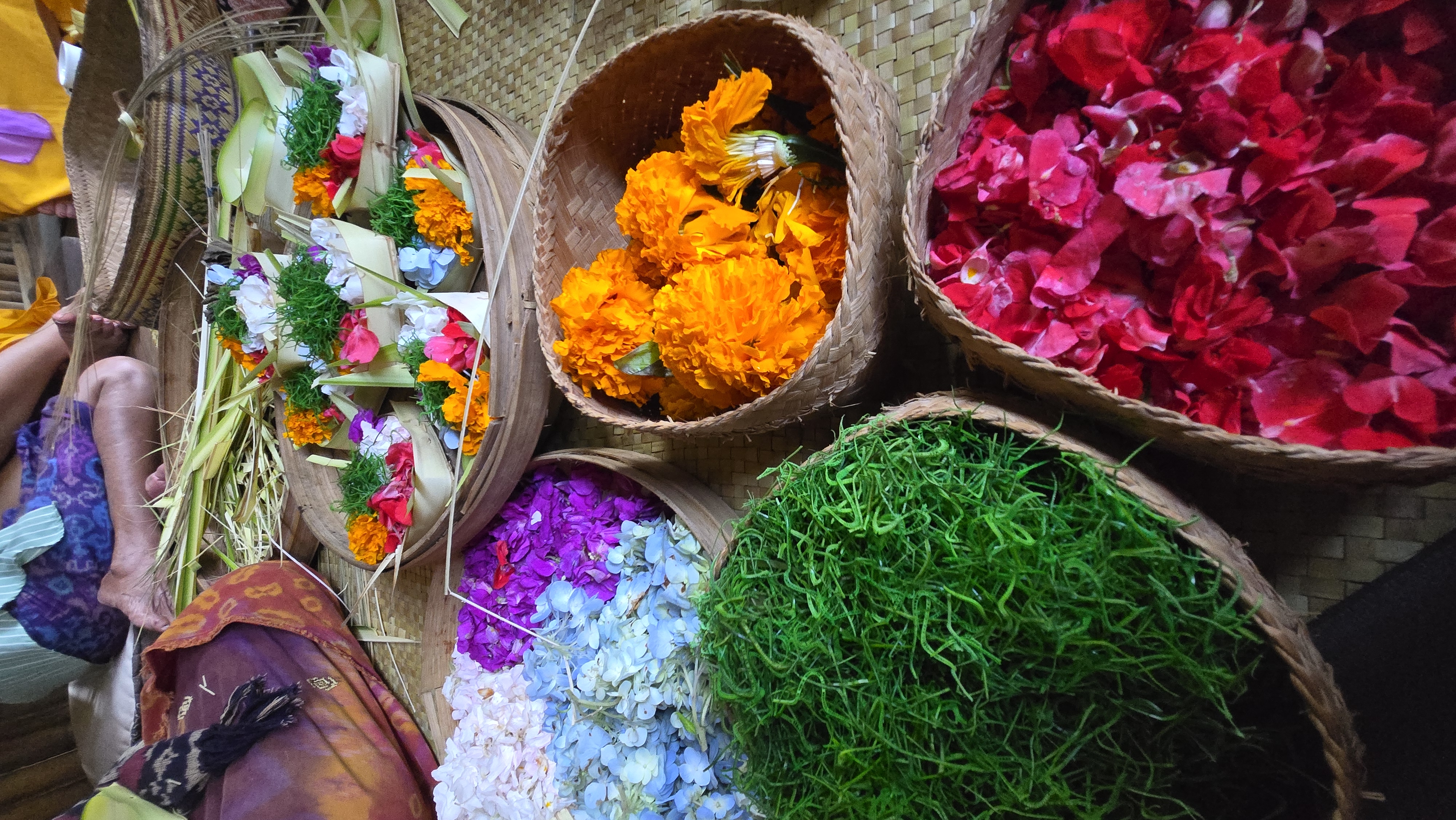 Overhead view of woven baskets filled with colorful flowers including marigolds, hydrangeas, and tropical blooms
