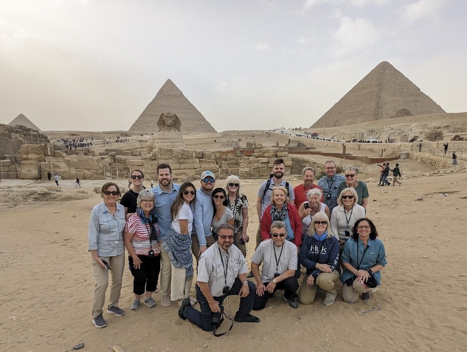 Large group of tourists posing together in front of the Great Pyramids and Sphinx at Giza, Egypt