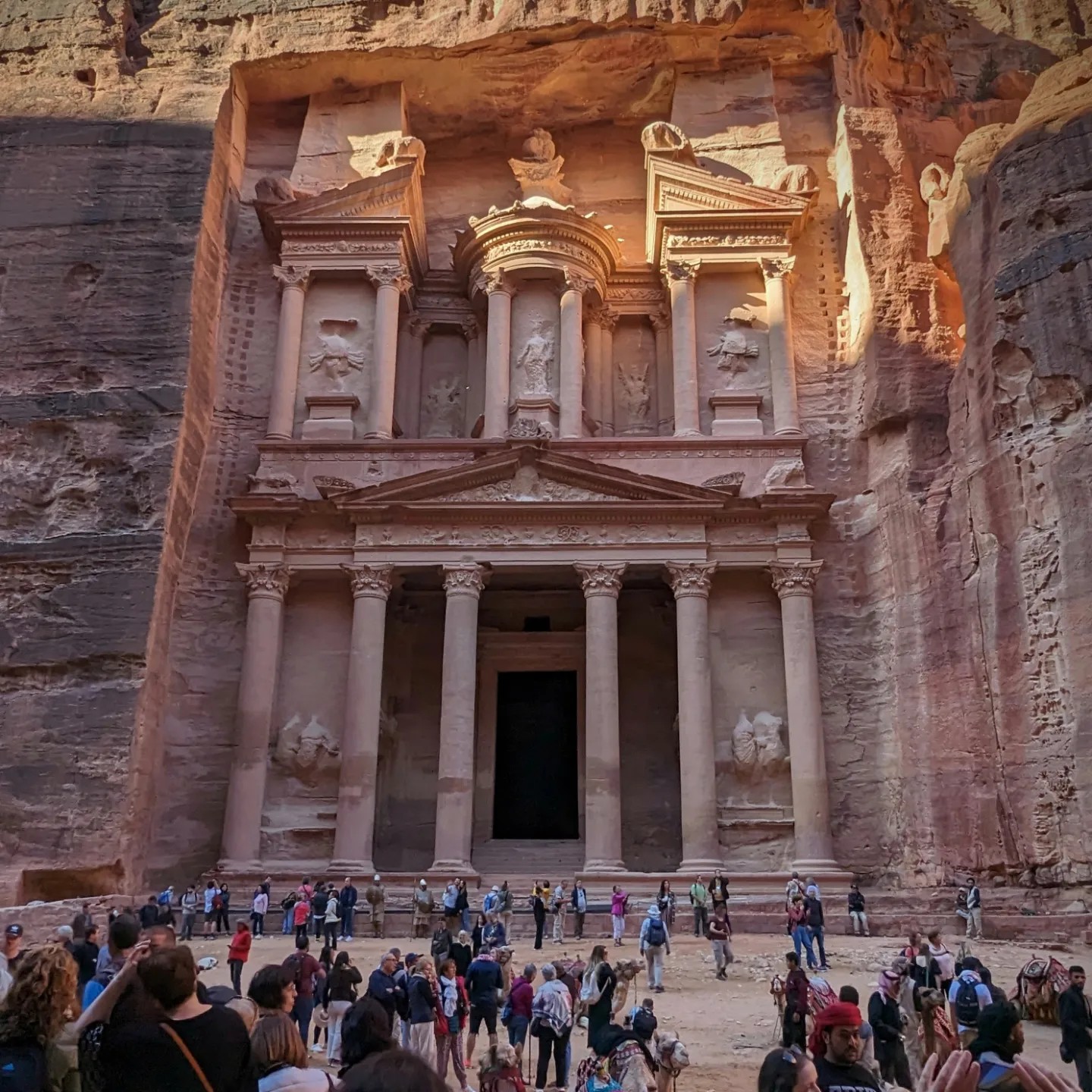 The ornate carved facade of Petra's Treasury building carved into rose-red sandstone cliffs, Jordan