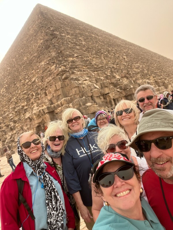 Julie and companions smiling at the camera with a pyramid visible in the background