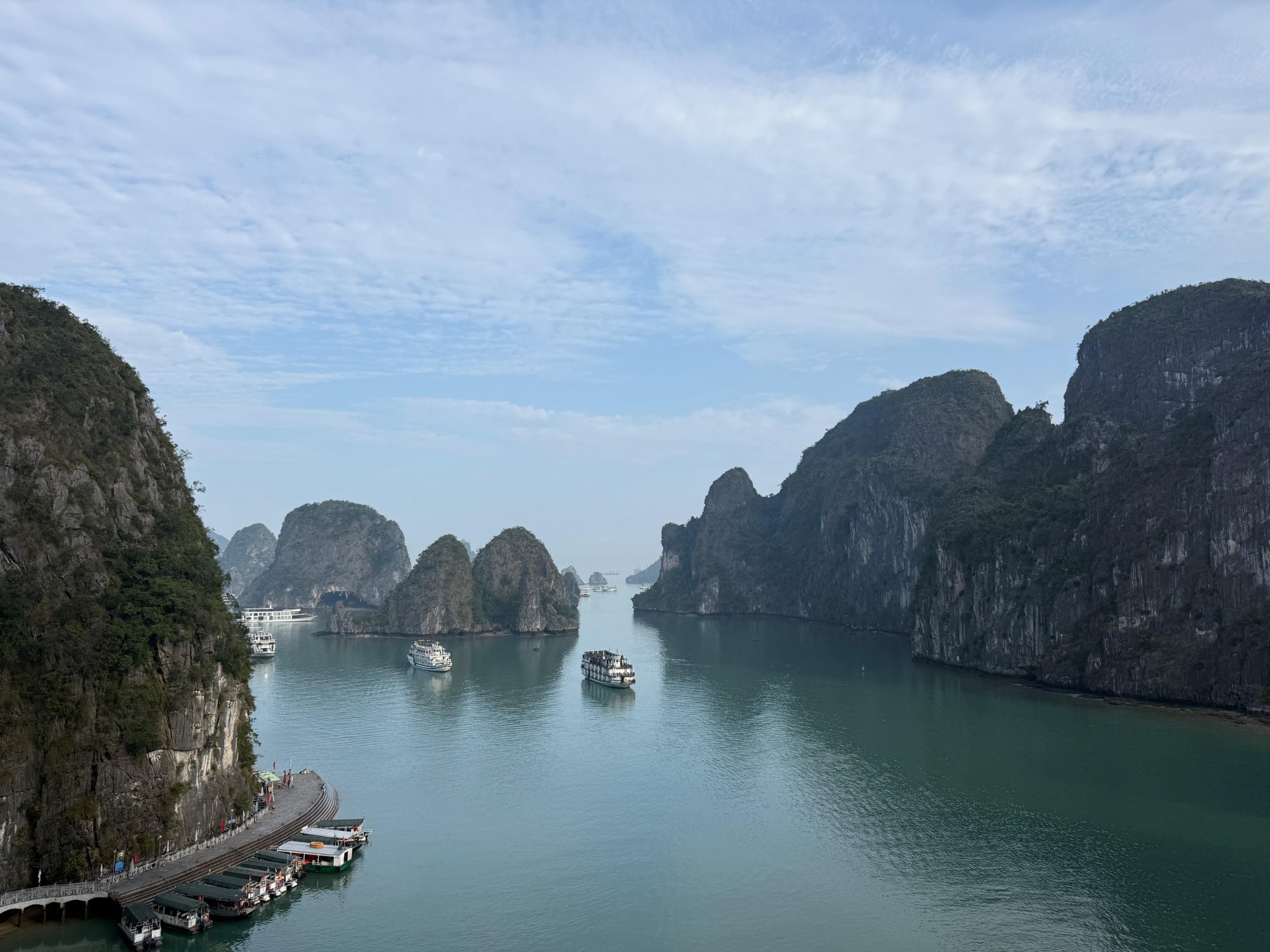 Wide view of Ha Long Bay showing multiple boats anchored among distinctive green-covered limestone peaks